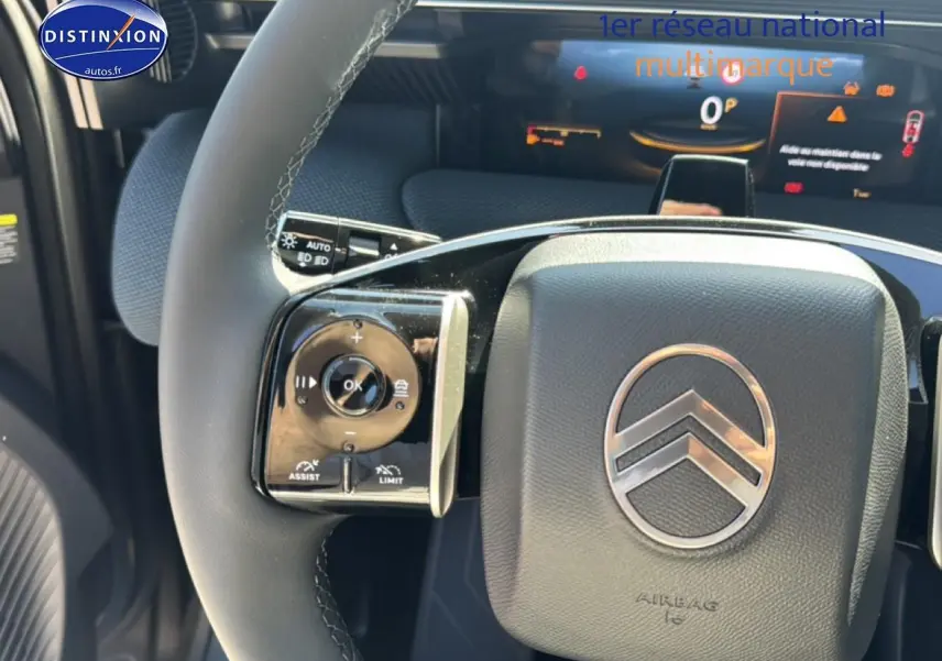 Gros plan sur le volant noir du Citroën C5 Aircross avec commandes multifonctions et logo chrome au centre.