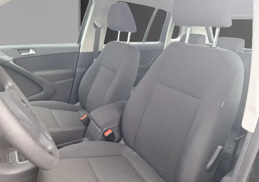 Vue intérieure du Volkswagen Tiguan 2014 montrant les sièges avant en tissu gris et la console centrale.