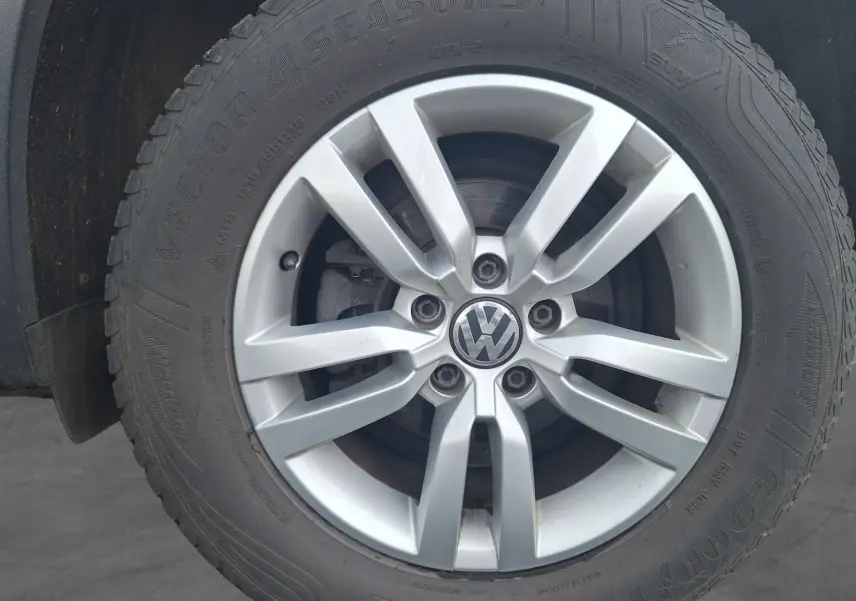 Gros plan sur la jante alliage 16 pouces argentée d’un Volkswagen Tiguan noir, vue latérale.