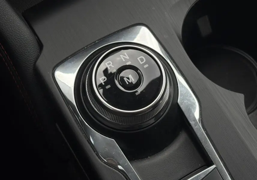 Gros plan sur le sélecteur rotatif de boîte automatique noir et chrome dans l'habitacle du Ford Kuga 2023.