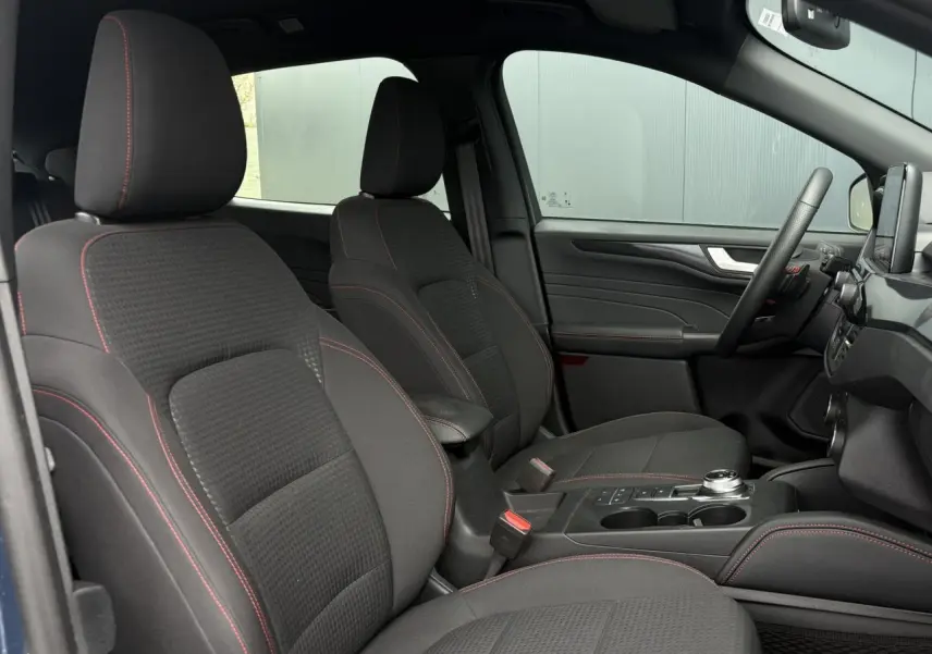 Vue intérieure côté droit du Ford Kuga 2023, sièges noirs avec surpiqûres rouges et console centrale avec sélecteur rotatif.