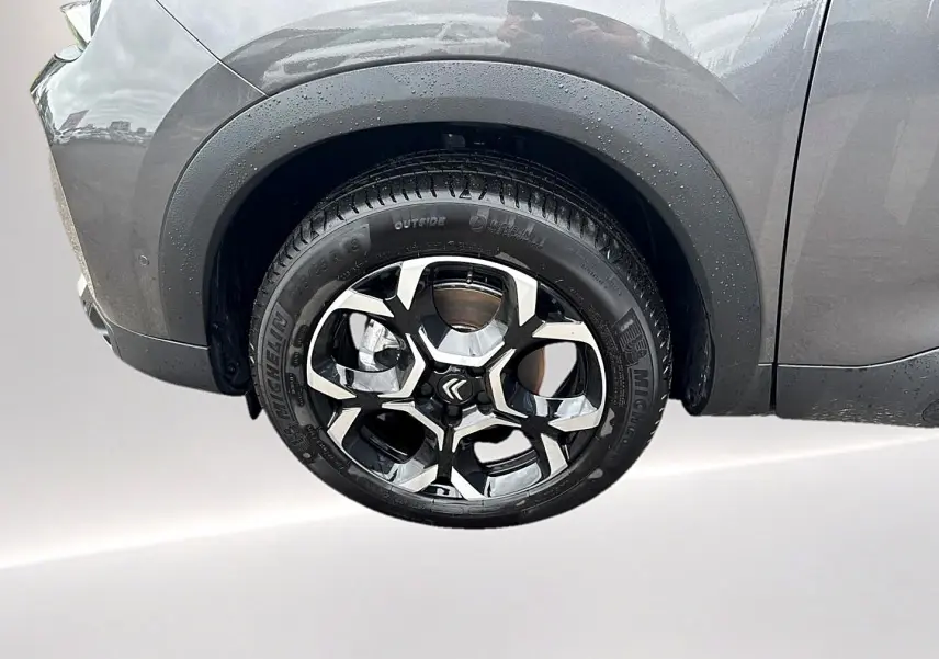 Gros plan sur la roue avant droite du Citroën C5 Aircross gris platinium avec jante alliage noire et argentée.