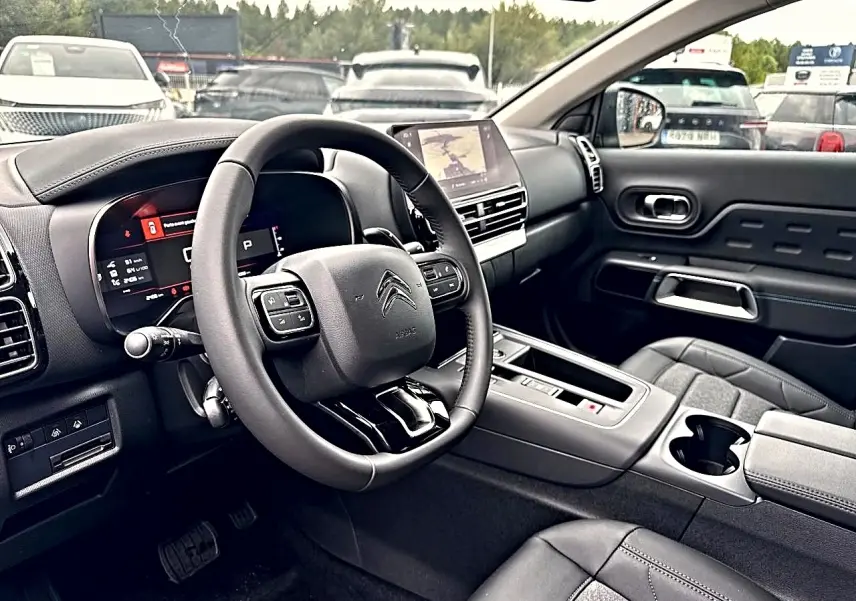 Vue intérieure côté conducteur du Citroën C5 Aircross 2025, volant cuir noir et écran tactile central visible.