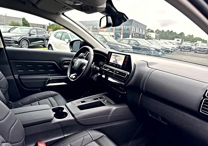 Vue intérieure côté conducteur du Citroën C5 Aircross 2025 avec tableau de bord noir et écran tactile central.