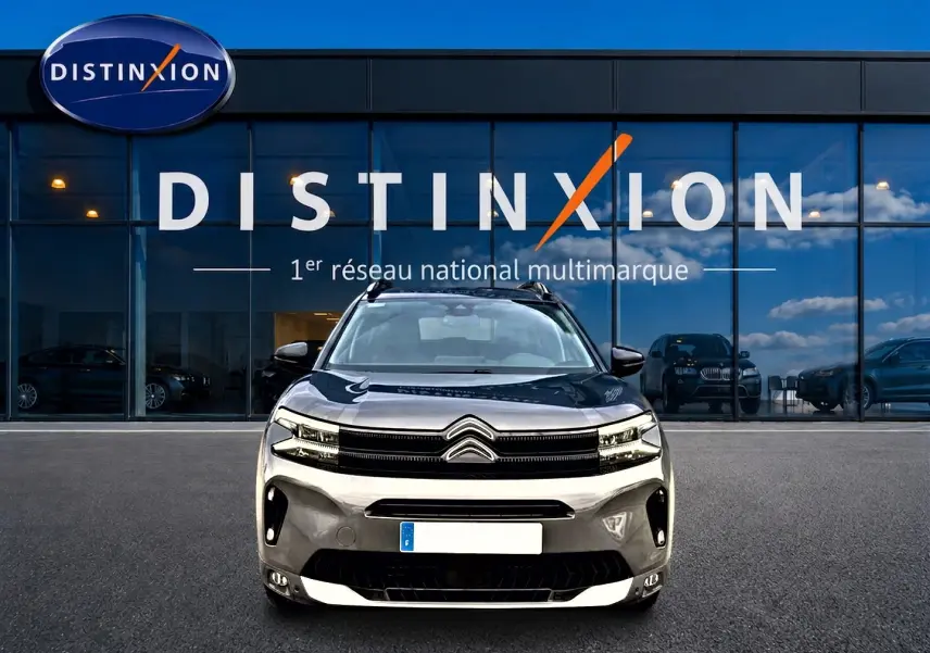 Vue avant d'un Citroën C5 Aircross gris platinium avec calandre noire et barres de toit visibles.