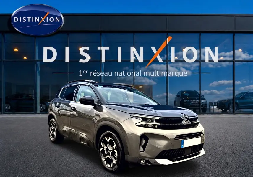 Citroën C5 Aircross gris platinium vue 3/4 avant droit avec jantes alu et barres de toit devant showroom Distinxion.