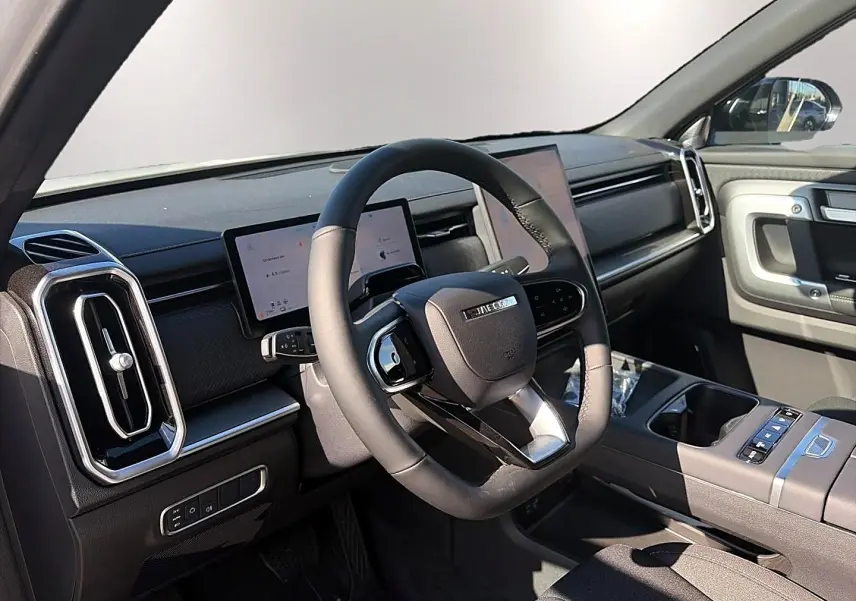 Vue intérieure côté conducteur du JAECOO J7 2026, volant multifonction noir et écran tactile double sur tableau de bord.