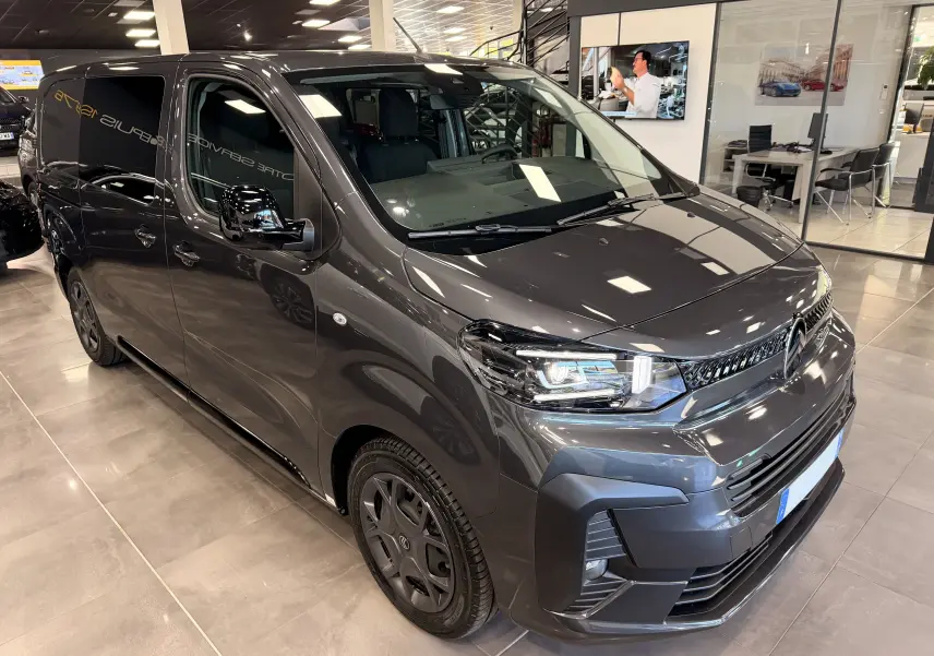 Vue 3/4 avant droit d’un Citroën Jumpy Cabine Approfondie gris titanium en showroom, avec phares LED allumés et jantes noires.