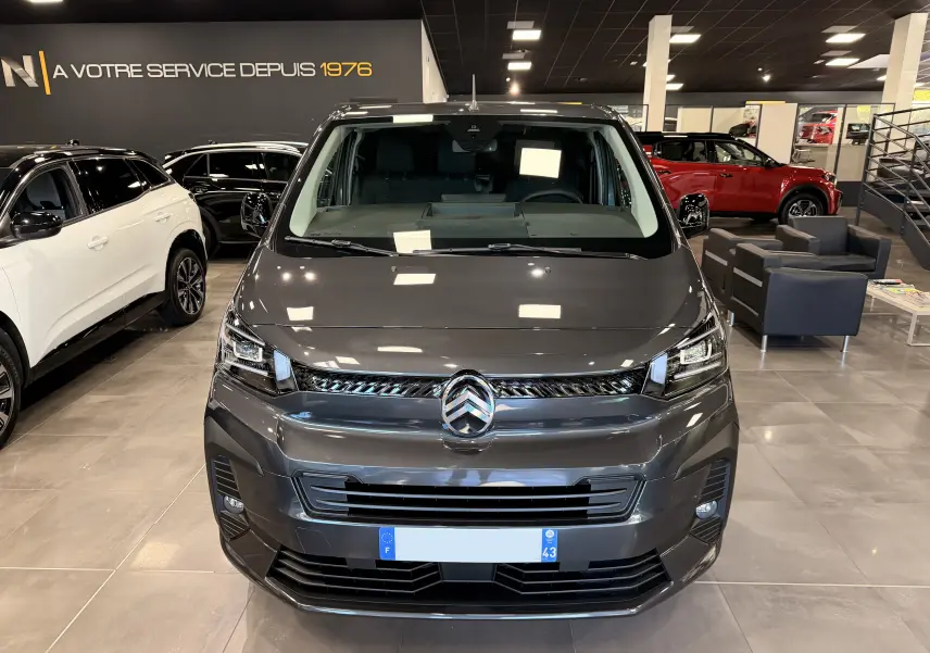 Vue frontale d’un Citroën Jumpy Cabine Approfondie gris titanium dans un showroom, mettant en valeur sa calandre moderne et ses phares LED.
