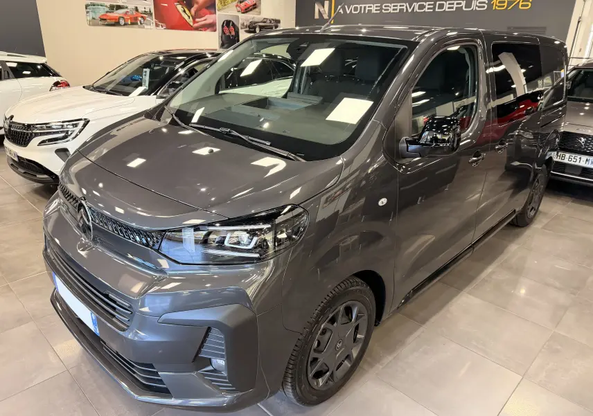 Vue 3/4 avant droit d'un Citroën Jumpy Cabine Approfondie gris titanium 2025 en showroom, avec phares LED et jantes noires.