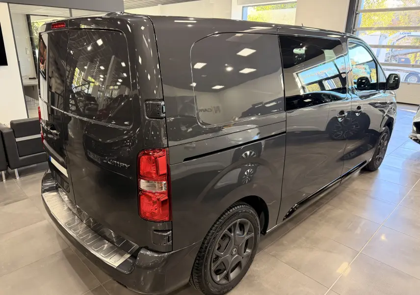 Vue 3/4 arrière droite du Citroën Jumpy Cabine Approfondie gris titanium avec porte latérale coulissante en showroom.