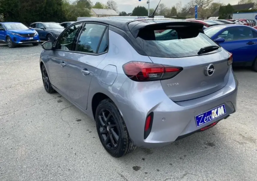 Opel Corsa gris magnetic vue 3/4 arrière droit, toit noir, jantes alliage noires et feux arrière LED visibles.