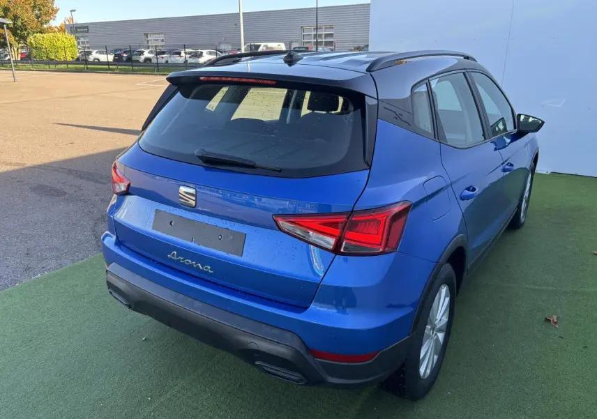 Vue 3/4 arrière droite d'un SEAT Arona bleu saphir avec toit noir, jantes alliage et feux arrière LED distinctifs.