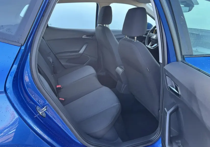 Vue intérieure côté arrière gauche d'une SEAT Arona bleu saphir avec sièges tissu noirs et portière ouverte.