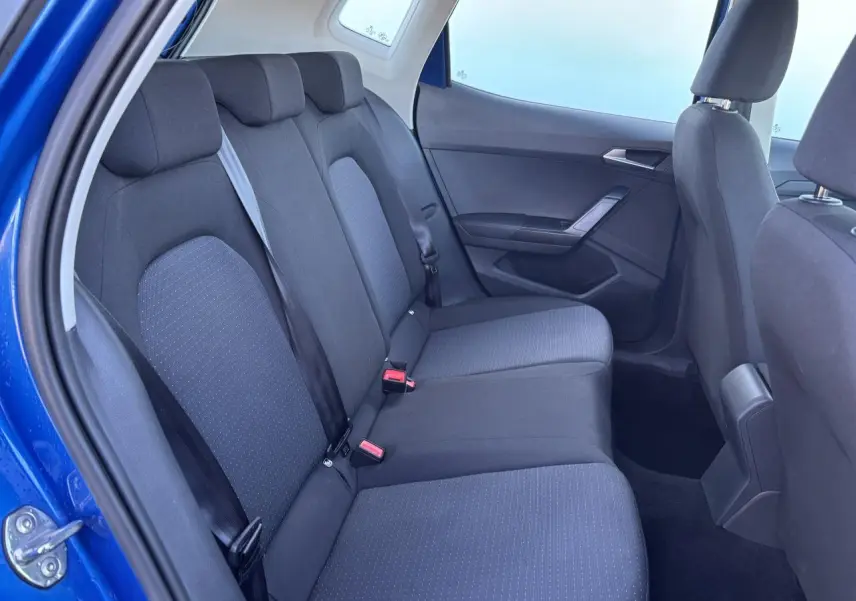 Vue intérieure côté arrière droit du SEAT Arona bleu saphir, montrant la banquette arrière en tissu noir.