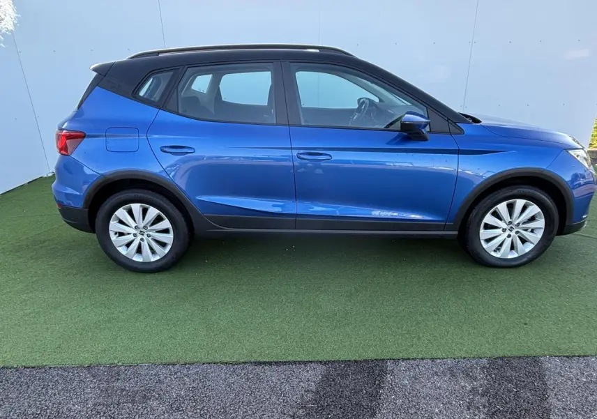 Vue de profil côté gauche d'un SEAT Arona 2024 bleu saphir avec toit noir et jantes alliage 16 pouces.
