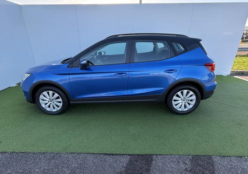 Vue de profil côté gauche d'une SEAT Arona 2024 bleu saphir avec toit noir et jantes alliage 16 pouces.