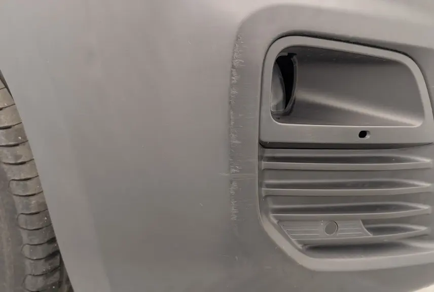 Gros plan sur la prise d'air noire côté gauche du pare-chocs avant du Citroën Berlingo Van blanc Banquise.