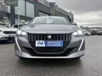 Vue de face d'une Peugeot 208 gris 1.2 PureTech 100 Style 2021 avec calandre distinctive et phares allumés.