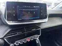 Vue intérieure du tableau de bord de la Peugeot 208 1.2 PureTech 100 Style 2021, avec écran tactile et commandes piano noires.