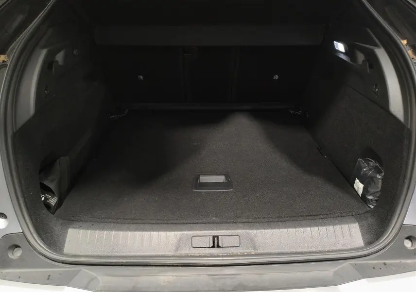 Coffre ouvert vu de l'arrière d'un Peugeot 3008 Hybrid gris Artense, espace de chargement vide et éclairé.