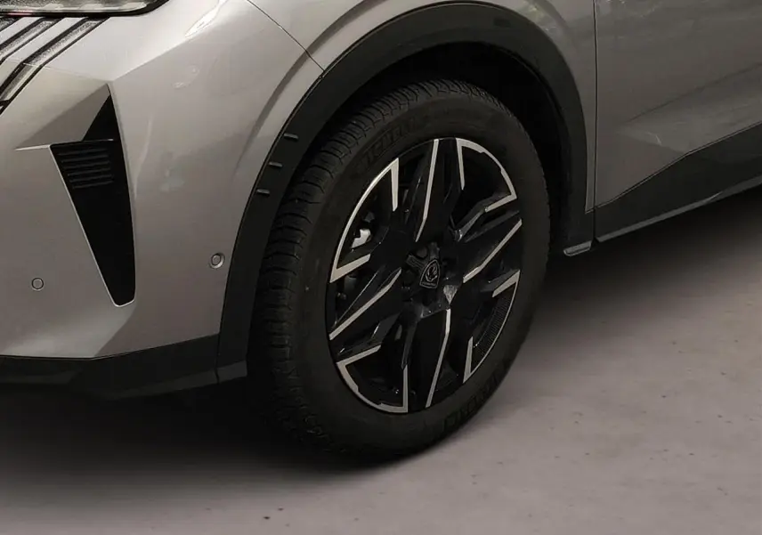 Gros plan sur la roue avant gauche et partie du pare-chocs gris Artense du Peugeot 3008 Hybrid 145 e-DSC6 GT.