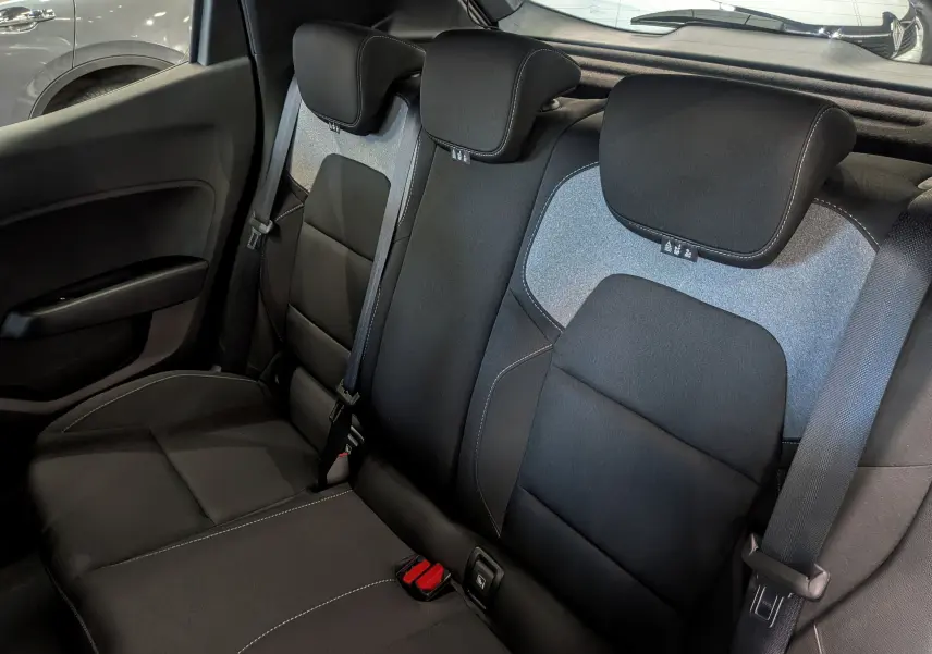 Vue intérieure de la banquette arrière en tissu noir et gris clair de la Renault Clio V 2025, avec ceintures de sécurité visibles.