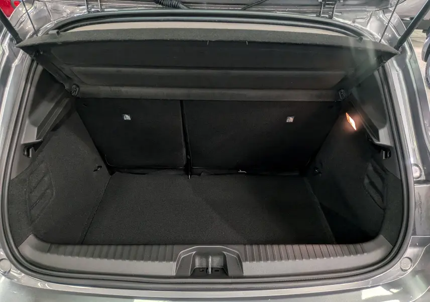 Coffre ouvert de Renault Clio V gris schiste, vue arrière montrant l'espace de chargement et l'éclairage intérieur à droite.