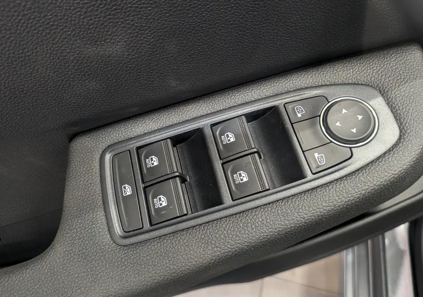 Gros plan sur les commandes de lève-vitres et réglage des rétroviseurs côté conducteur, finition tissu noir.