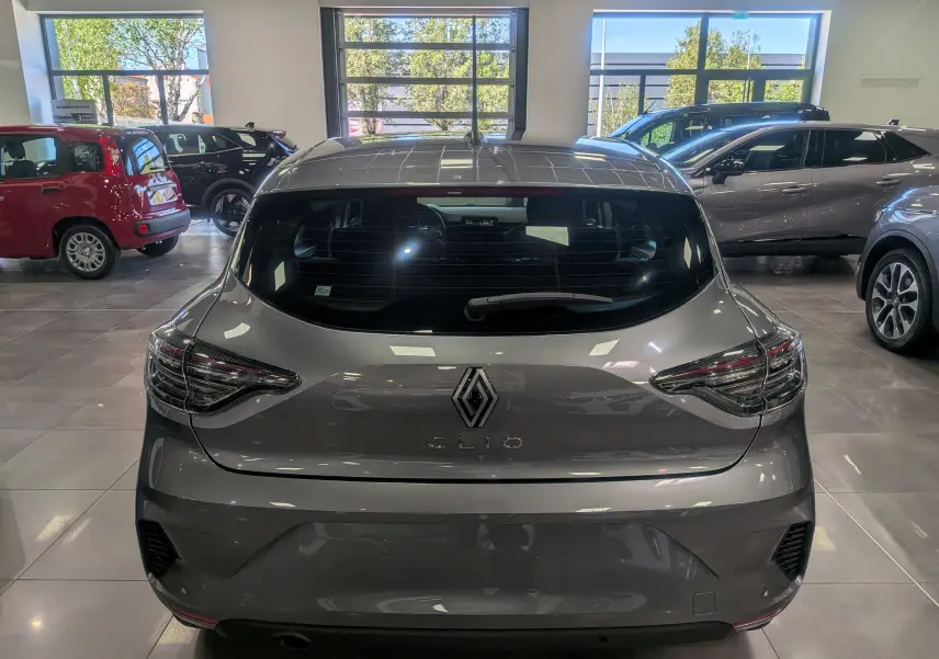 Vue arrière d'une Renault Clio V gris schiste dans un showroom, mettant en valeur ses feux arrière et son logo central.