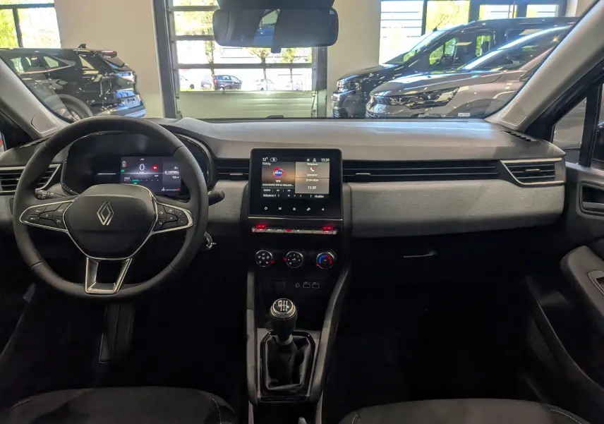 Vue intérieure frontale du tableau de bord de la Renault Clio V gris schiste avec écran tactile et boîte manuelle.