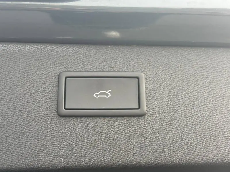 Bouton noir d'ouverture électrique du coffre sur tableau de bord intérieur du CUPRA Formentor bleu 2025.