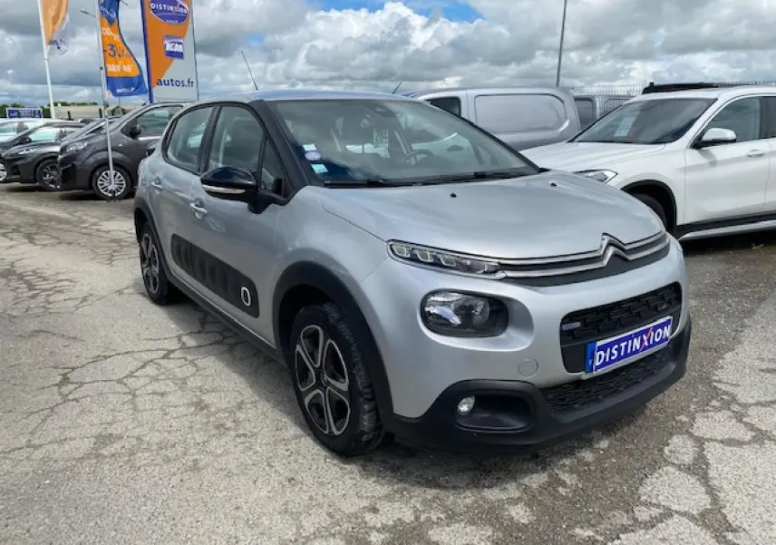 Citroën C3 gris clair vue 3/4 avant droit, avec protections latérales noires et jantes stylisées.