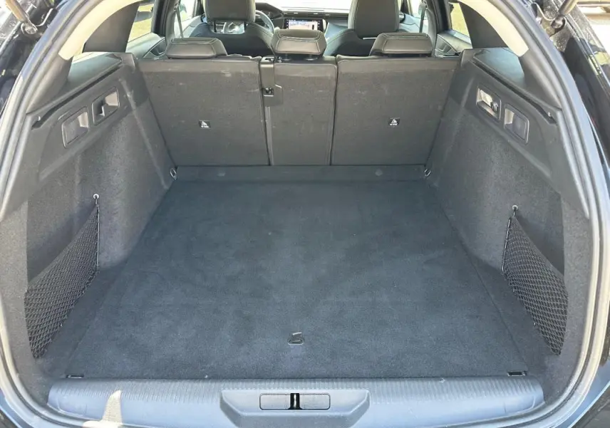 Coffre ouvert vu de l’arrière d’une Peugeot 308 SW Hybrid noire, montrant un espace de chargement propre et spacieux.