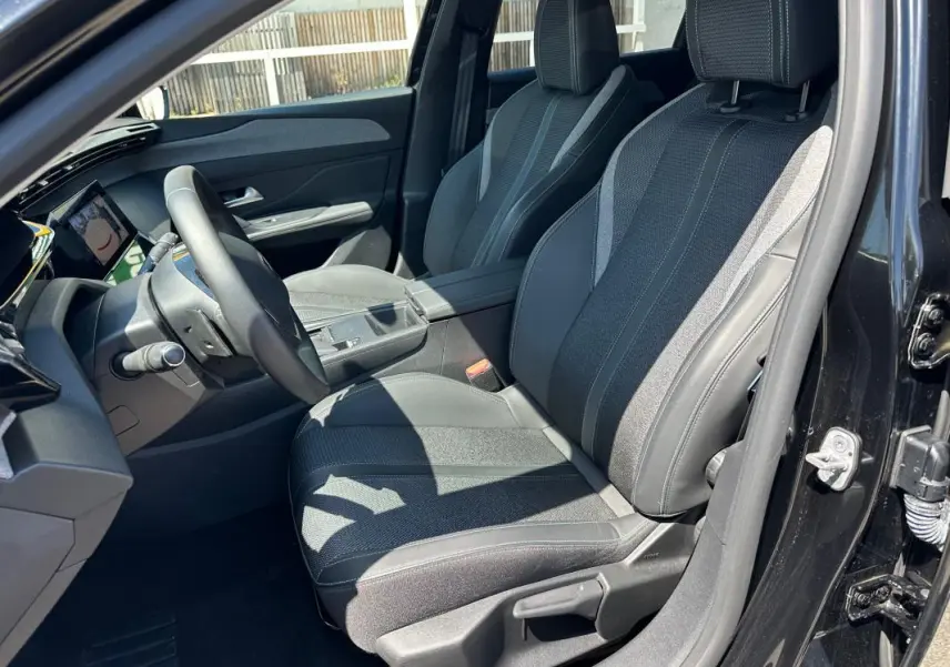 Intérieur avant droit du Peugeot 308 SW Hybrid 145 noir, montrant les sièges en tissu et cuir avec détails contrastants.