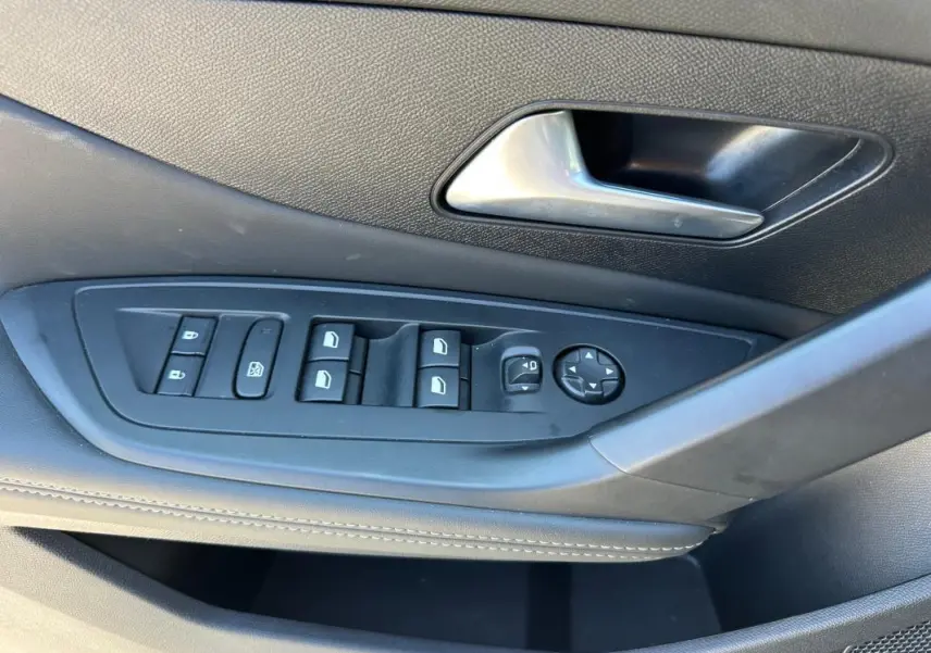 Gros plan sur la commande des vitres et rétroviseurs côté conducteur du Peugeot 308 SW Hybrid noir, finition Allure 2025.
