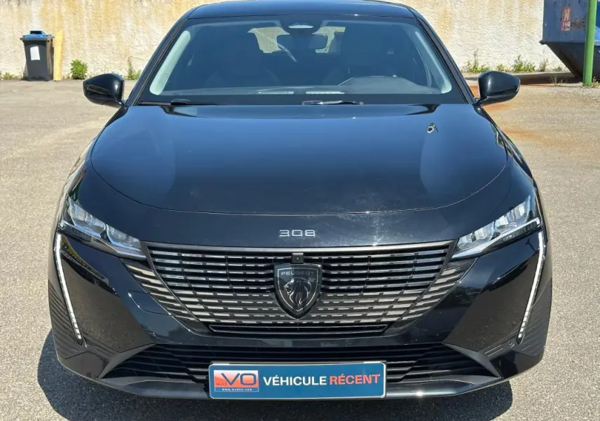 Vue frontale d'une Peugeot 308 SW Hybrid noire 2025 avec calandre distinctive et logo Peugeot central.