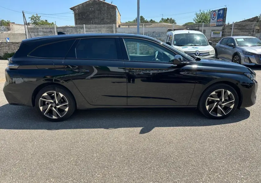 Peugeot 308 SW Hybrid 145 e-DCS6 Allure noir vue de profil côté gauche, stationnée en extérieur au soleil.