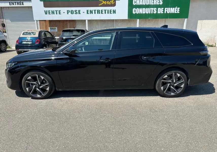 Profil côté gauche d'une Peugeot 308 SW Hybrid 145 e-DCS6 Allure noire, finition 2025 avec jantes alliage distinctives.
