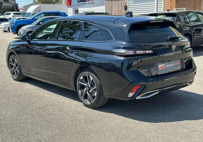 Peugeot 308 SW Hybrid noir vue 3/4 arrière droit, avec feux arrière distinctifs et jantes alliage modernes.