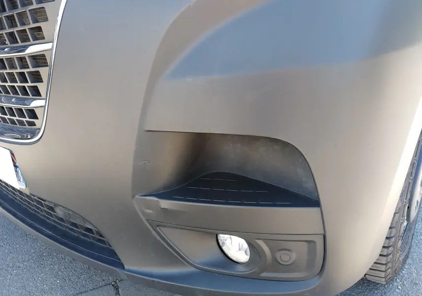 Gros plan sur le pare-chocs avant droit blanc du Renault Master III avec antibrouillard et capteur de stationnement.