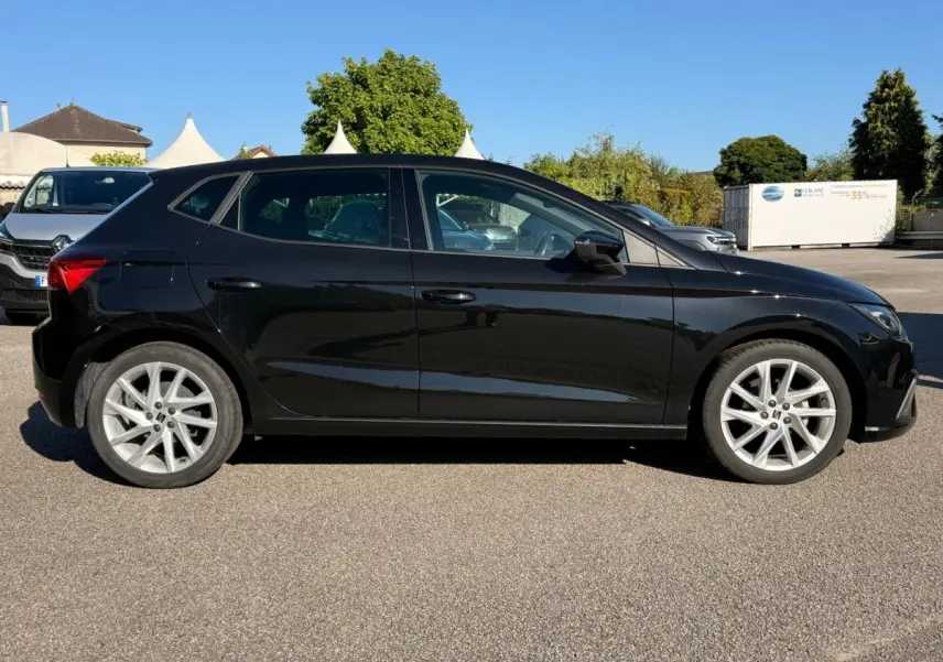 Vue arrière d'une SEAT Ibiza 1.0 TSI FR noire, avec feux LED triangulaires et double sortie d'échappement chromée.