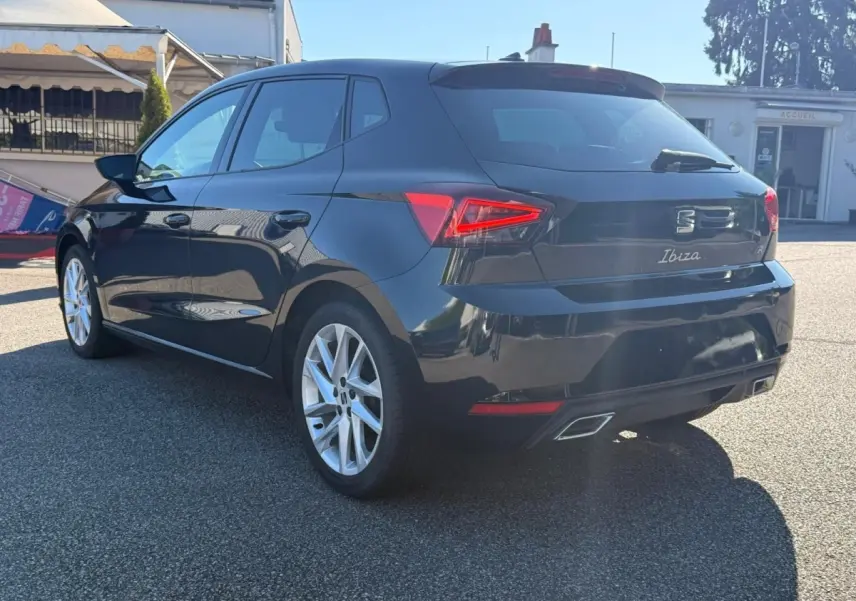 Vue intérieure avant du poste de conduite de la SEAT Ibiza noire, volant cuir multifonctions et écran tactile central.