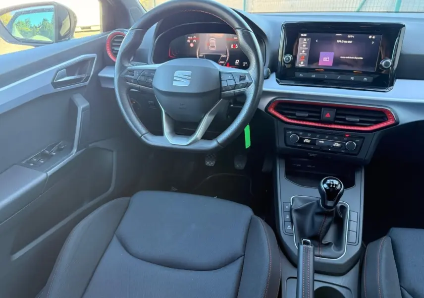 Vue intérieure centrée sur le volant cuir noir perforé de la SEAT Ibiza 2025 avec tableau de bord digital et écran tactile.