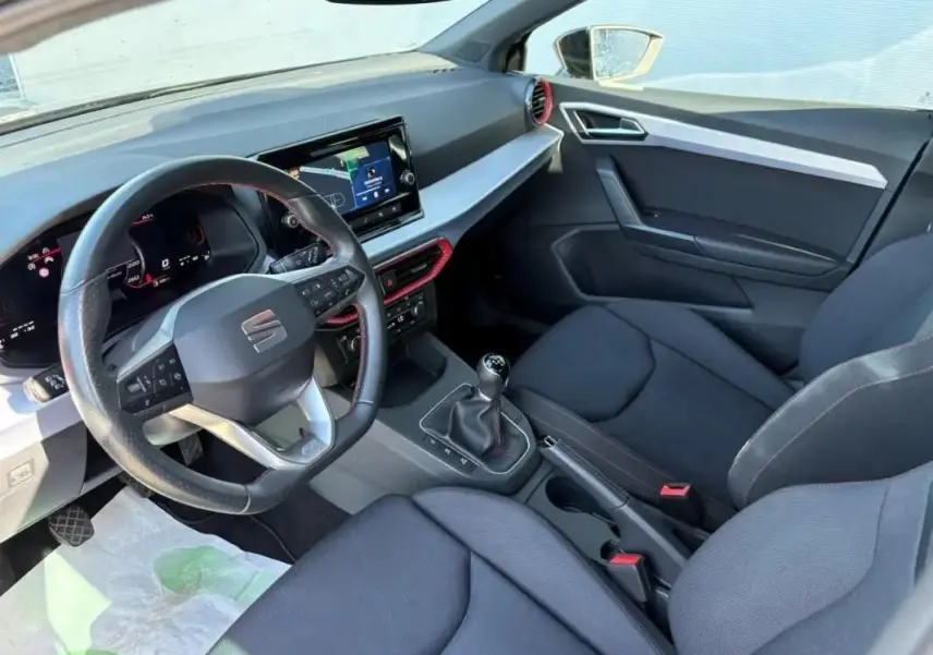 Vue intérieure côté conducteur de la SEAT Ibiza 1.0 TSI 95 FR 2025, volant cuir, écran tactile et sellerie noire.