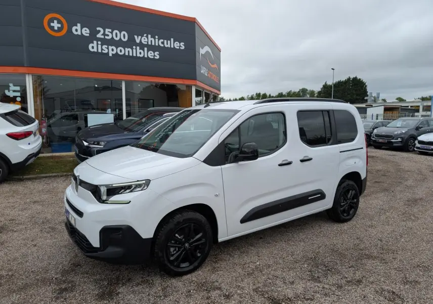 Citroën Berlingo blanc en 3/4 avant droit avec barres de toit noires et jantes alliage noires.