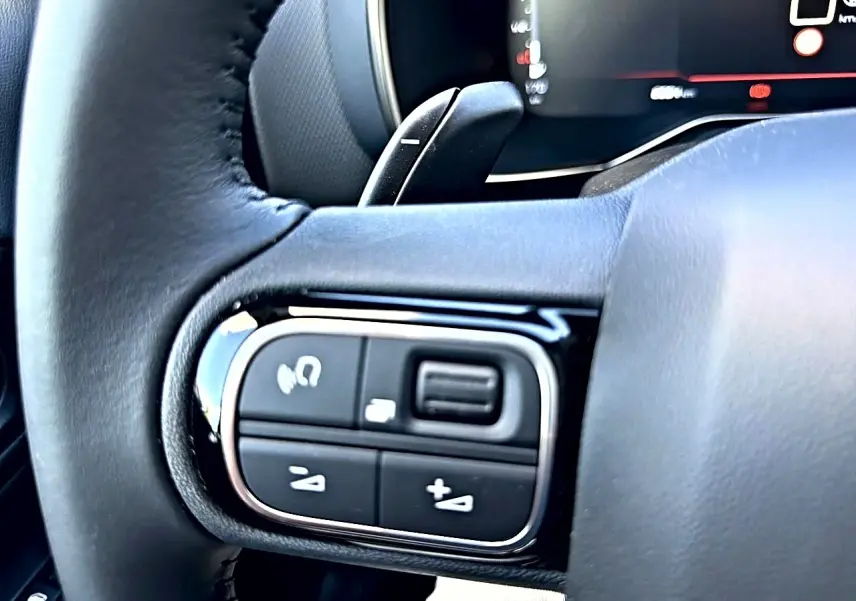 Gros plan sur les commandes multifonctions gauche du volant cuir du Citroën C5 Aircross 2025 blanc.