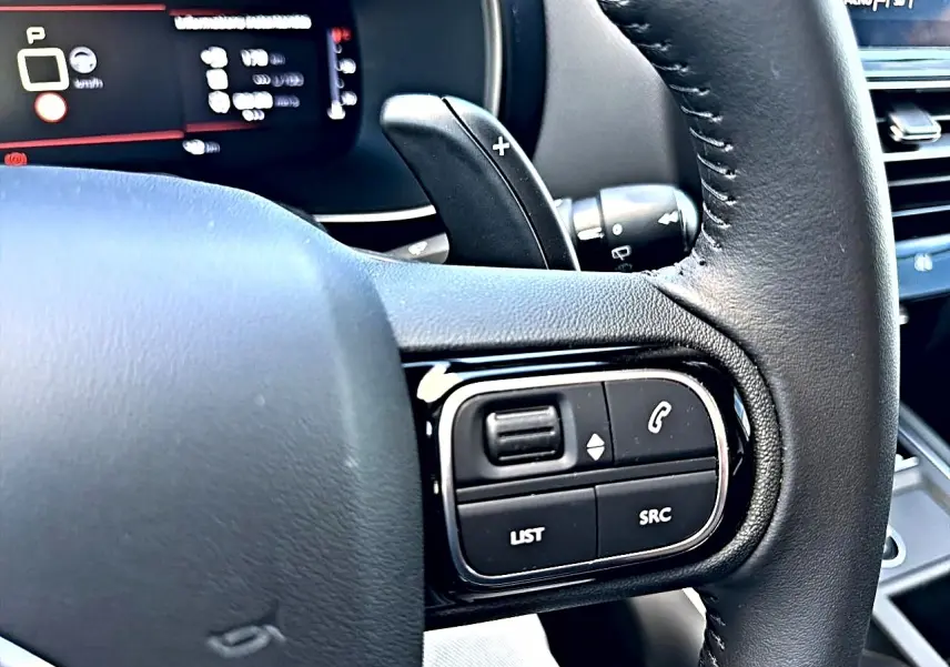 Gros plan sur le volant cuir noir côté gauche du Citroën C5 Aircross avec commandes multifonctions visibles.