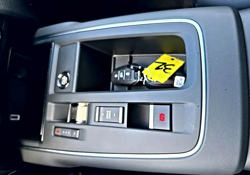 Vue rapprochée de la console centrale grise avec clé et bouton de frein à main électrique dans Citroën C5 Aircross blanc.