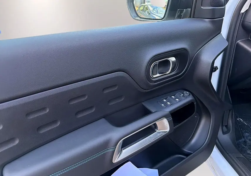 Vue intérieure côté conducteur de la porte noire du Citroën C5 Aircross blanc avec commandes des vitres et poignée argentée.